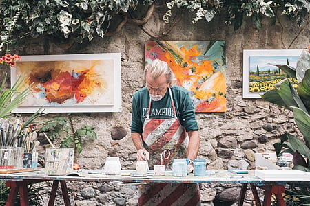 man wearing blue Champion long-sleeved shirt with red and white striped apron standing in front of wooden table thumbnail