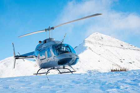 helicopter landing on snow near mountain thumbnail