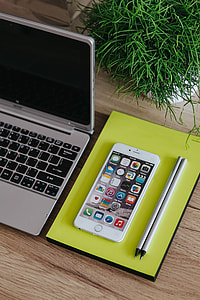 Silver Acer laptop, a white Apple iPhone and a notepad on a wooden desk thumbnail