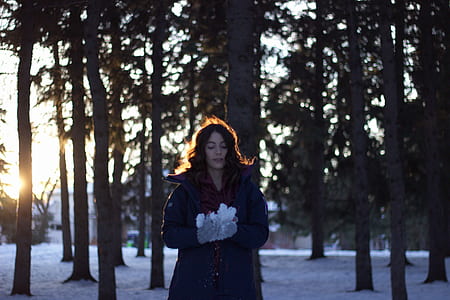 woman standing on snowy ground in the middle of forest thumbnail