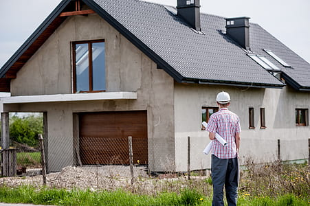 man with hardhat looking at gray concrete house thumbnail