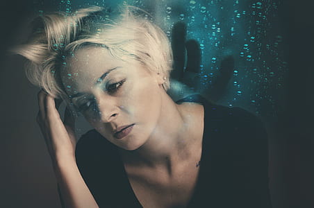 woman in black top tilting her head while touching hair thumbnail