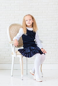 yellow haired girl in blue and white dress sitting on chair thumbnail