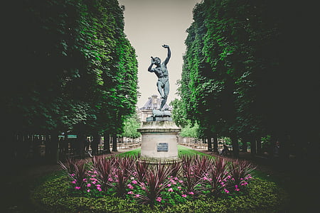 man statue near tall trees at daytime thumbnail