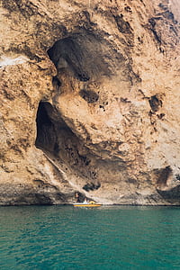 two person riding on yellow boat near brown rock formation at day time thumbnail