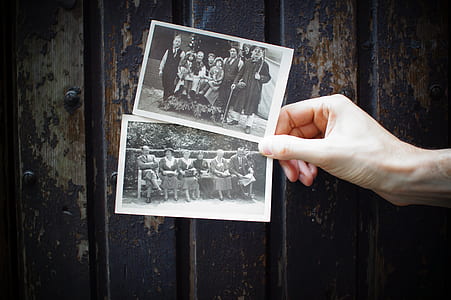 person holding grayscale photos of people sitting thumbnail