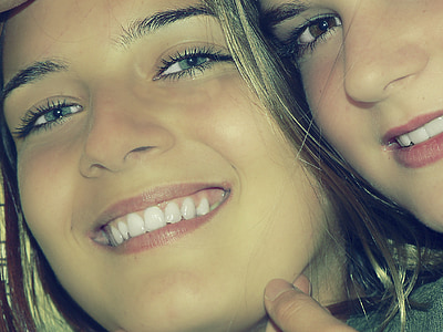 two woman taking closeup photo thumbnail
