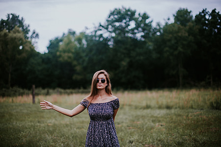 woman standing wearing blue dress near green field grass during daytime thumbnail