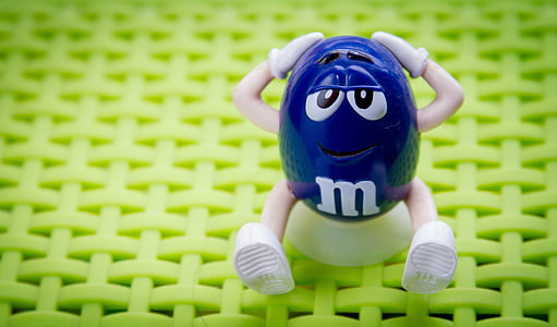 blue M&M's figurine sitting on stool] thumbnail
