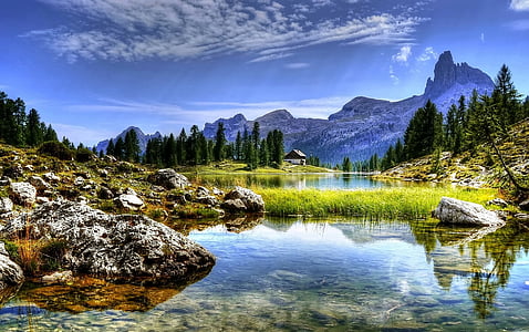 body of water near mountains and trees during daytime thumbnail