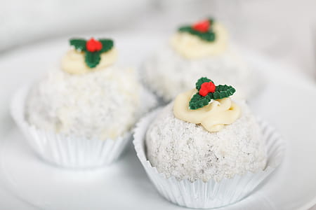 three cupcakes coated with white powder with cream toppings in selective focus photography thumbnail