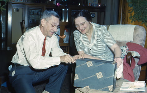 smiling woman sitting on chair holding box with man helping her thumbnail