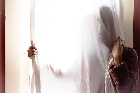 person hiding behind curtain inside room thumbnail
