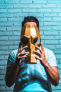 person standing in front wall holding mask thumbnail