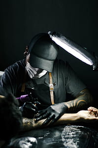 Tattoo artist in black gloves drawing a tattoo on a person's arm thumbnail