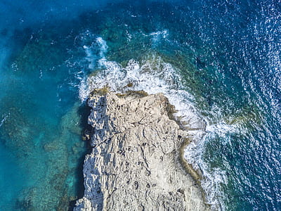 gray rock formation surrounded by body of water thumbnail