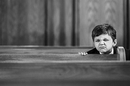 grayscale photography of boy sitting on pew thumbnail