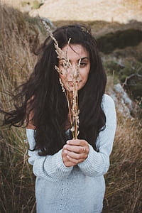 woman in grey long-sleeved shirt holding dried grass while standing thumbnail