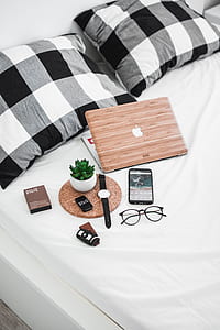 silver MacBook beside succulent plant and watch on top of mattress thumbnail