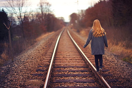 woman wearing gray suit jacket walking on train tracks thumbnail