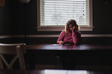 Woman in pink shirt writing on paper on a table thumbnail