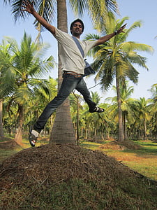 man wearing white crew-neck t-shirt jumping behind palm tree thumbnail