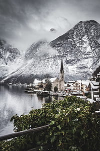 brown buildings near snow-capped mountain thumbnail