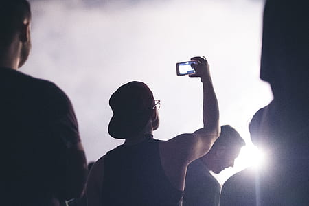 man standing with crowd while taking photo of sky thumbnail