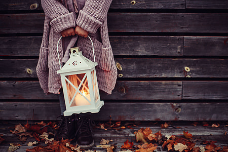 person in gray knit coat holding white lamp thumbnail