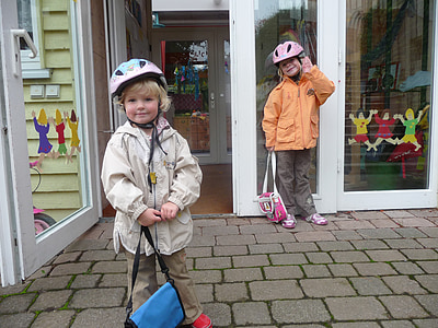 two children's wearing jackets and bicycle helmets thumbnail