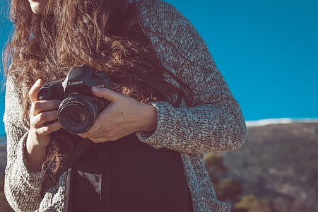 woman wearing brown knit cardigan holding camera thumbnail