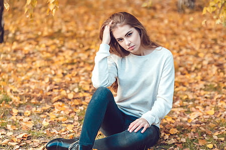 woman sitting on green grass touching head with right hand thumbnail