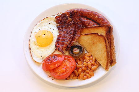 fried sunny side-up egg, sliced tomatoes, toast bread, sausage, ham and beans on white ceramic plate thumbnail