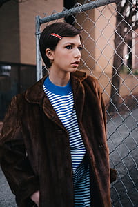 woman wearing brown coat standing beside fence thumbnail