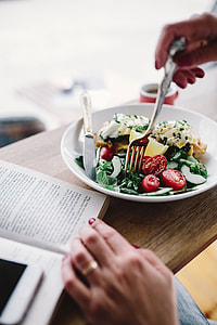 Woman eating breakfast and reading a book thumbnail