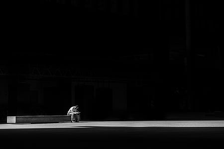 grayscale photo of man sitting on bench thumbnail