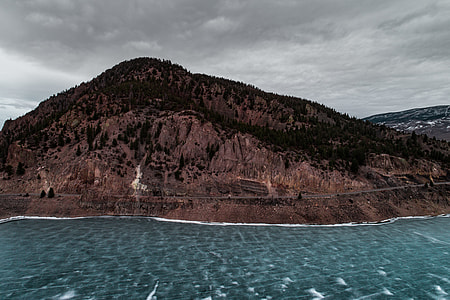 landscape photo of brown mountain near shore thumbnail