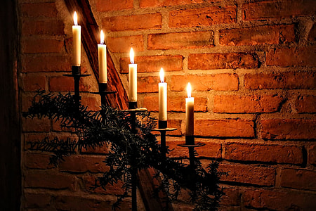 five lighted candles on candlesticks near brown brick wall thumbnail