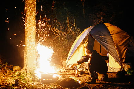 man in front bonfire near tent at nighttime thumbnail