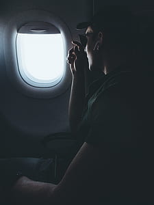 person wearing wireless earphones looking outside airplane window thumbnail