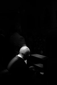 grayscale photo of man sitting on pew bench thumbnail