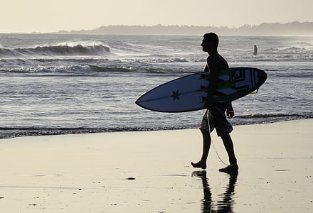 man holding surfboard on shore thumbnail