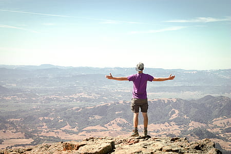 photography of man standing on rock mountain thumbnail