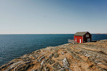 red house on cliff across the ocean thumbnail