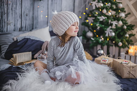 girl in gray long-sleeved shirt and knit cap sitting on white fur textile thumbnail
