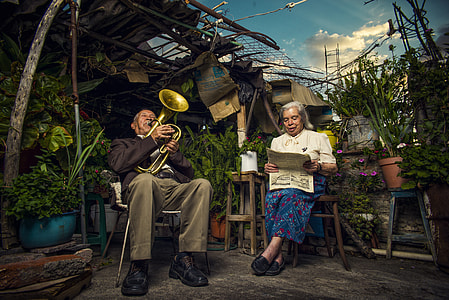 man playing wind instrument near woman reading newspaper thumbnail