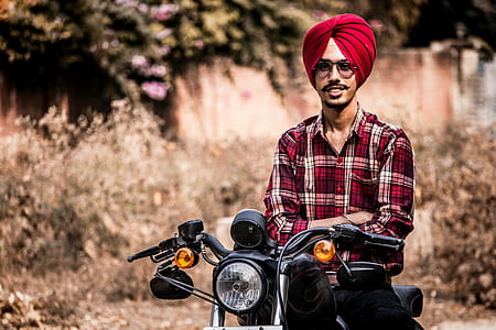 man in red and white plaid sport shirt and red turban on black motorcycle closeup photography thumbnail