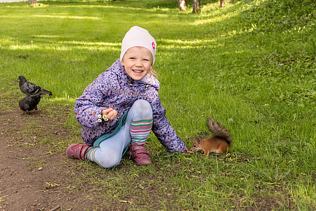 girl wearing purple jacket beside squirrel thumbnail