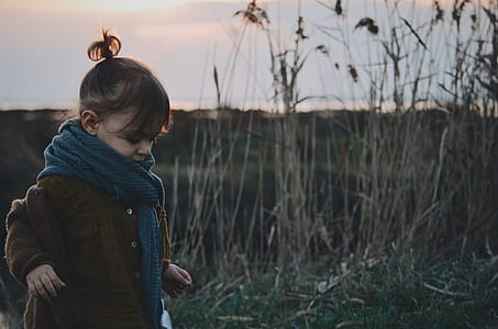 girl brown and blue wearing scarf standing near brown grass at daytime thumbnail