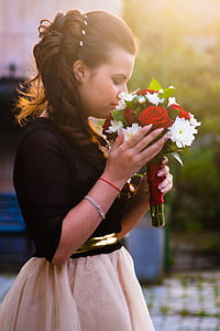 shallow focus photography of a woman holding bouquet of white and red flowers thumbnail